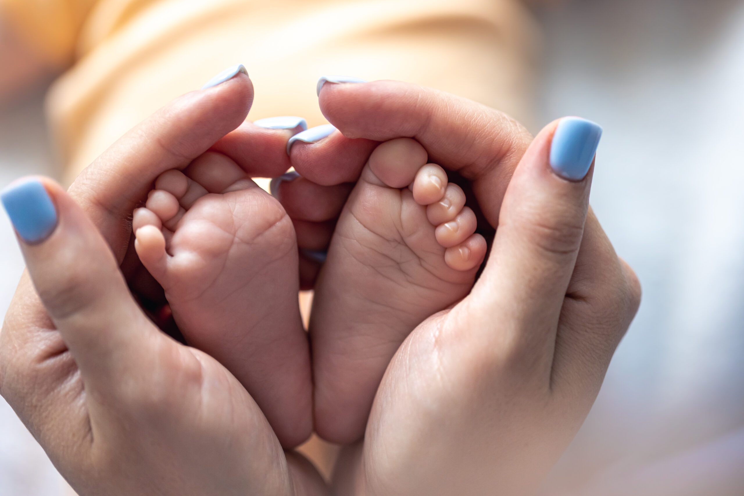 mom holds the legs of a newborn baby in her hands.